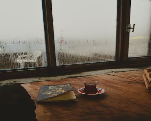 Secangkir teh hangat dan buku jurnal di atas meja kayu